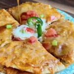 Copycat Mexican pizza on a turquoise plate with melted cheese, sour cream and jalapeno