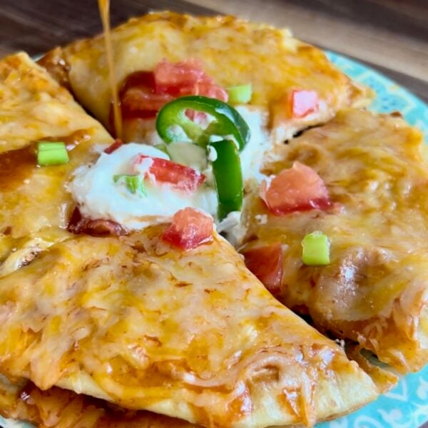 Copycat Mexican pizza on a turquoise plate with melted cheese, sour cream and jalapeno