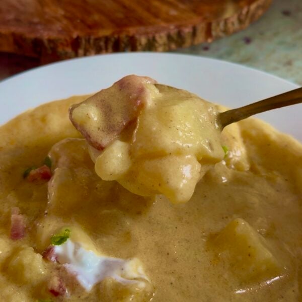 Spoonful of loaded baked potato soup with tender potato chunks, bacon and sour cream