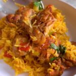 Plated chicken and rice with saffron-colored rice, tender chicken and cilantro