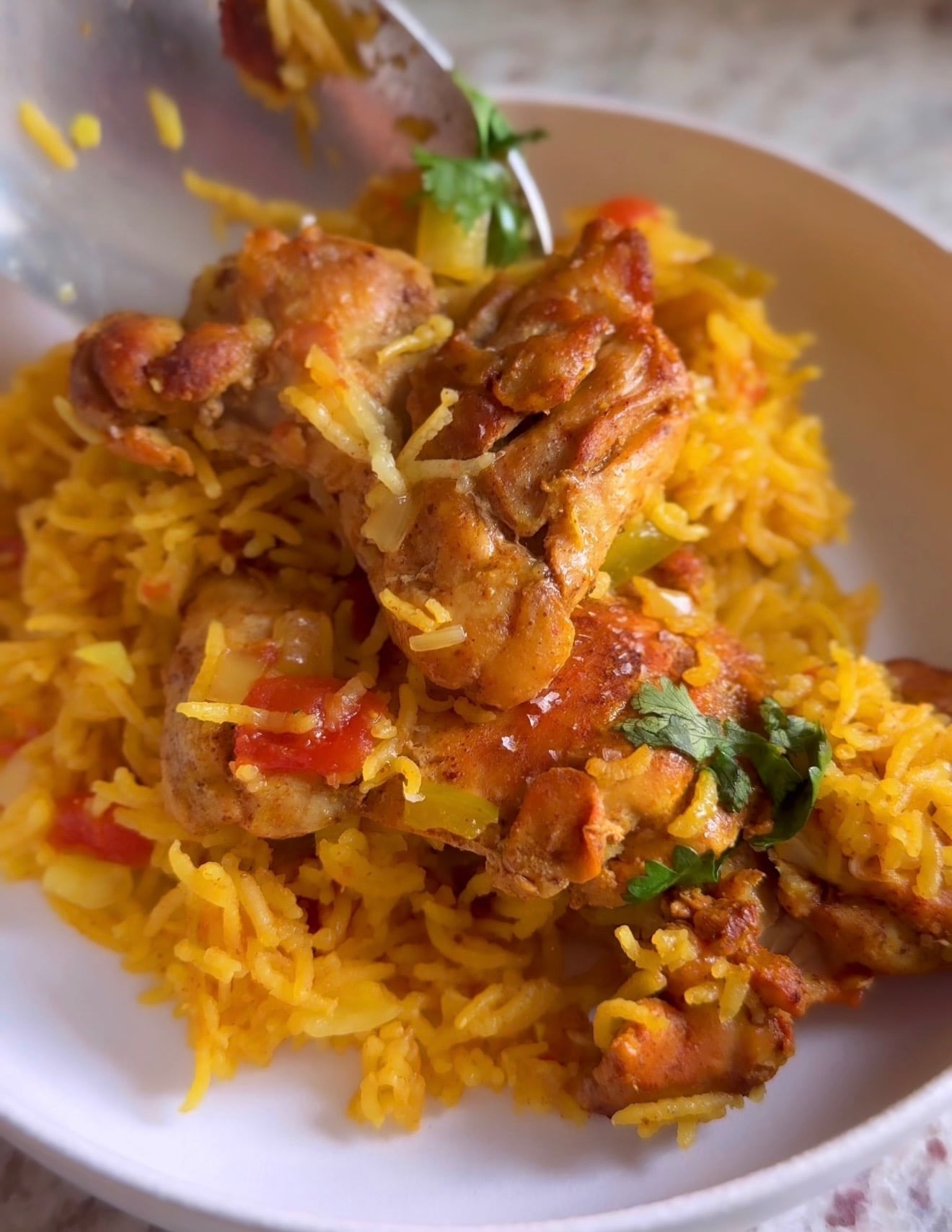 Plated chicken and rice with saffron-colored rice, tender chicken and cilantro