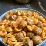 Mini meatballs and orecchiette in creamy tomato sauce, served in a pale blue bowl