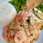 Creamy mushroom sauce spooned over seared salmon with rice and fresh greens