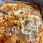 Golden baked chicken alfredo lasagna in a sheet pan, spatula lifting a cheesy slice