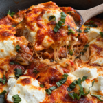 Skillet of deconstructed lasagna with ricotta dollops, melted cheese and torn basil