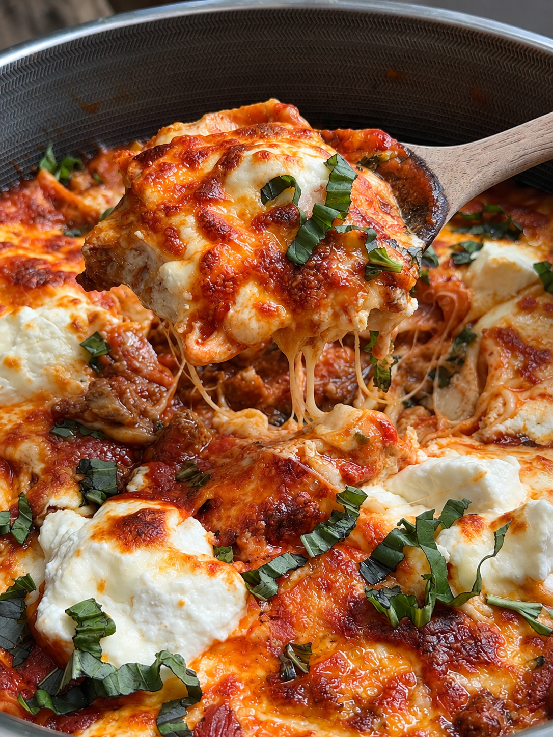 Skillet of deconstructed lasagna with ricotta dollops, melted cheese and torn basil