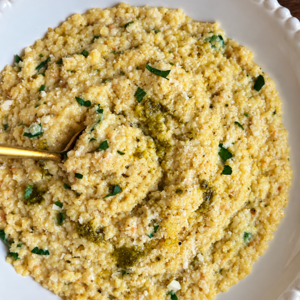 Creamy garlic parmesan pastina swirled with pesto in a white bowl