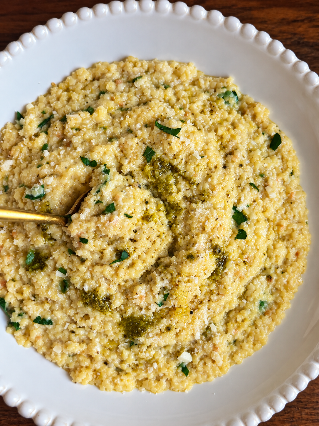 Creamy garlic parmesan pastina swirled with pesto in a white bowl
