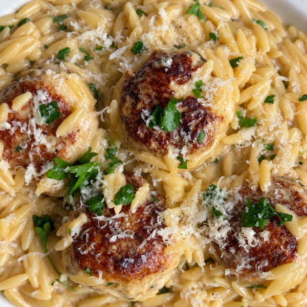 Browned chicken meatballs over creamy orzo with parmesan and chopped parsley