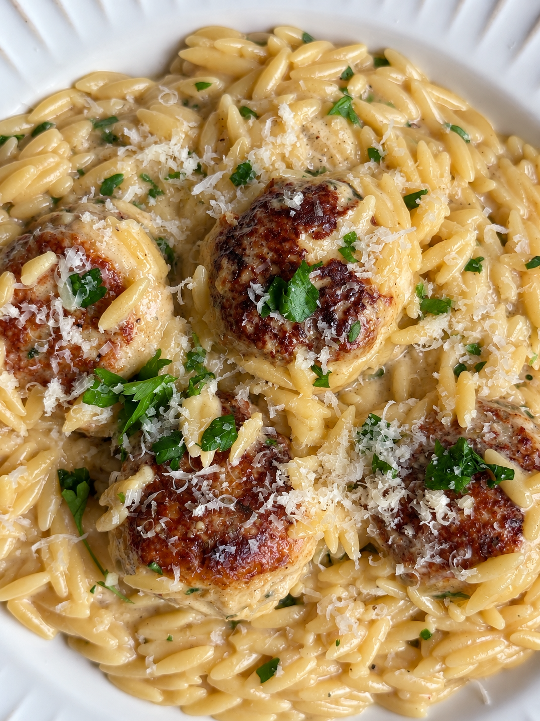 Browned chicken meatballs over creamy orzo with parmesan and chopped parsley