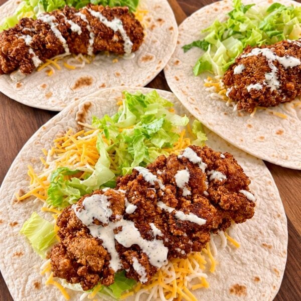 Crispy chicken snack wraps with shredded lettuce, cheddar and ranch drizzle on flour tortillas