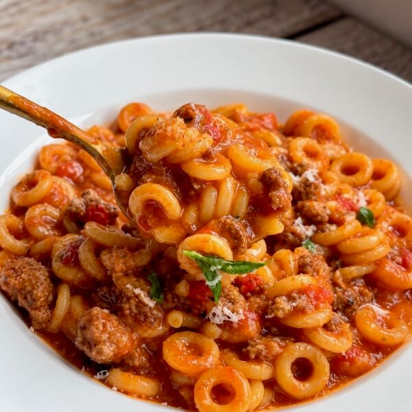 Gold spoon in a bowl of homemade Spaghetti-O's with mini meatballs and chopped parsley