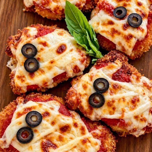 Chicken parmesan cutlets decorated as mummies with mozzarella strips and olive eyes