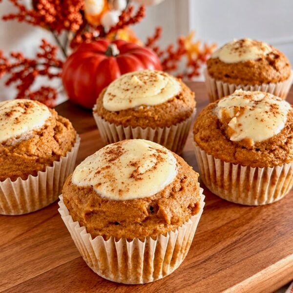 Pumpkin muffins topped with a cream cheese swirl and a dusting of cinnamon
