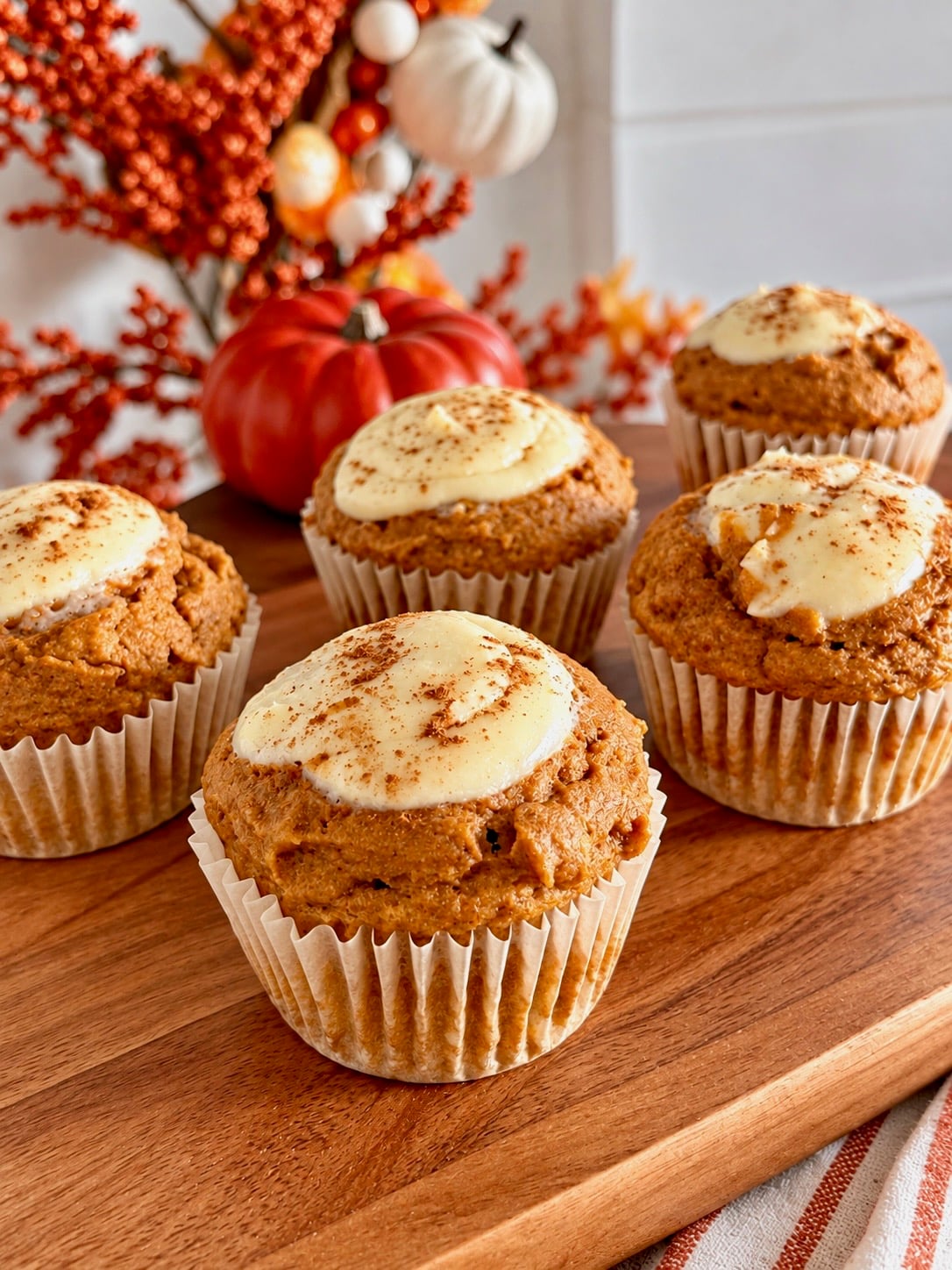 Pumpkin muffins topped with a cream cheese swirl and a dusting of cinnamon