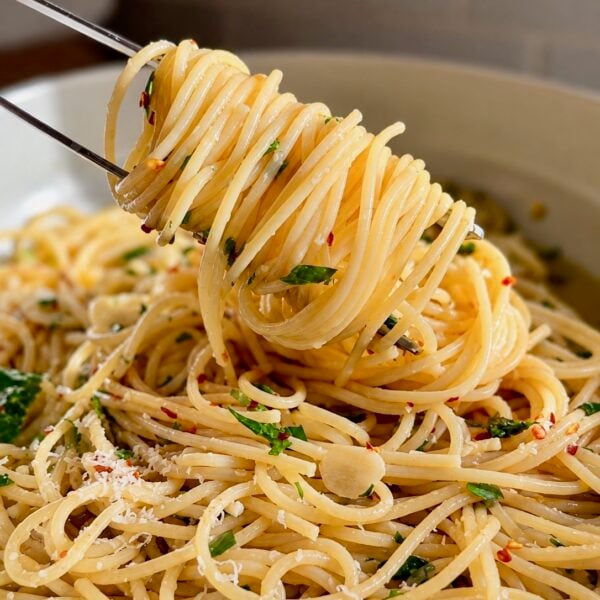 Fork twirling spaghetti aglio e olio flecked with parsley and red pepper flakes
