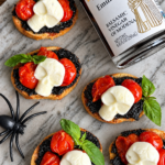 Spooky caprese bruschetta with ghost-shaped mozzarella, cherry tomatoes and basil on marble