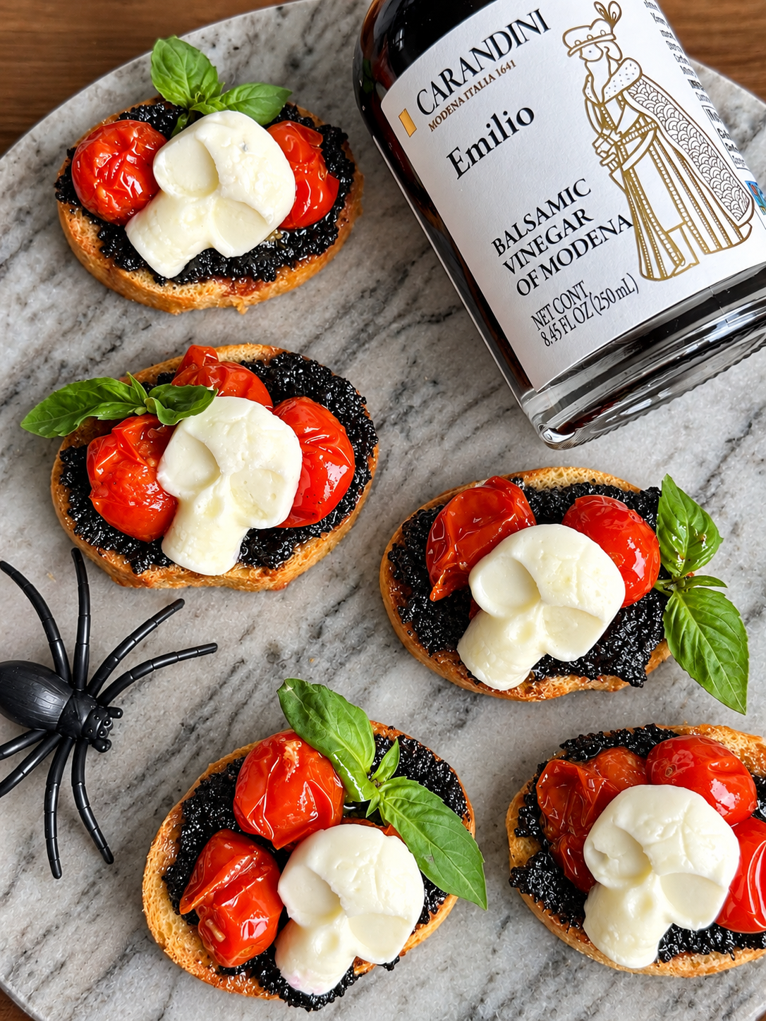 Spooky caprese bruschetta with ghost-shaped mozzarella, cherry tomatoes and basil on marble