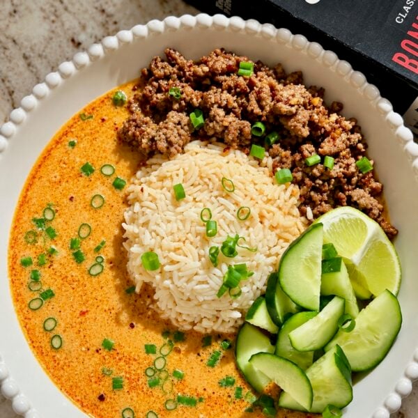 Coconut broth bowl with ground beef, jasmine rice, cucumber and lime wedges